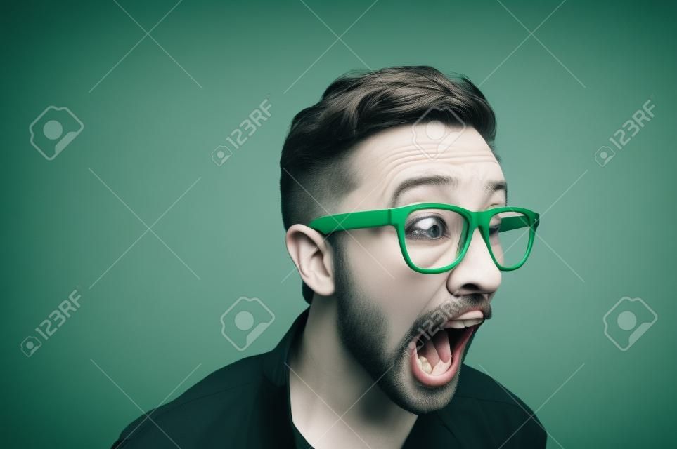 在灰色背景下用绿色眼镜尖叫的男人