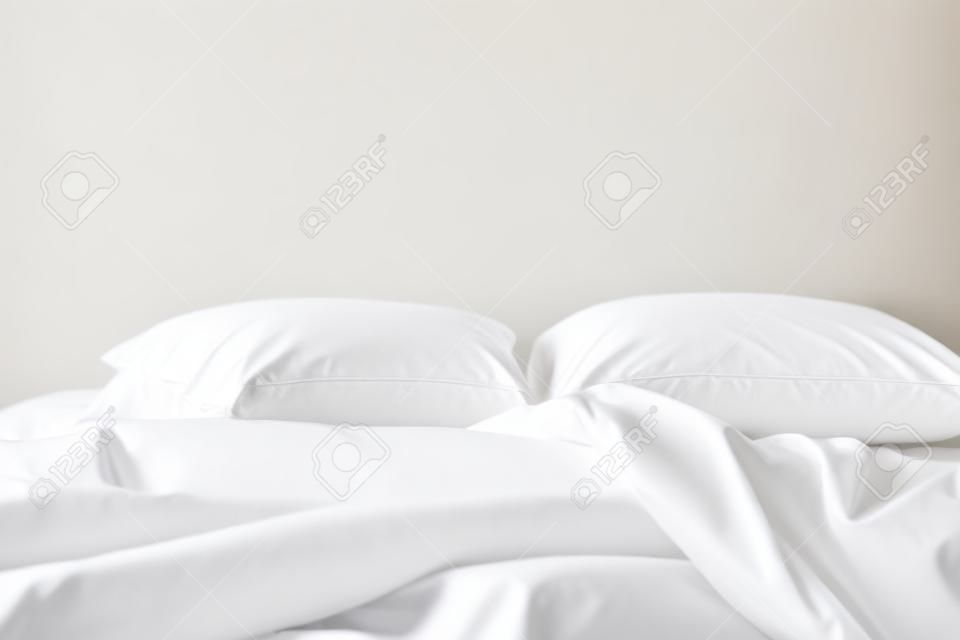 Закройте белые постельные принадлежности простыни и подушки на белом фоне