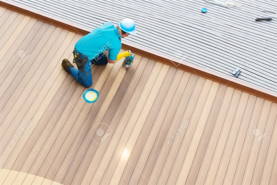 Een werker schilderen buitenkant houten zwembad dek, Bovenaanzicht