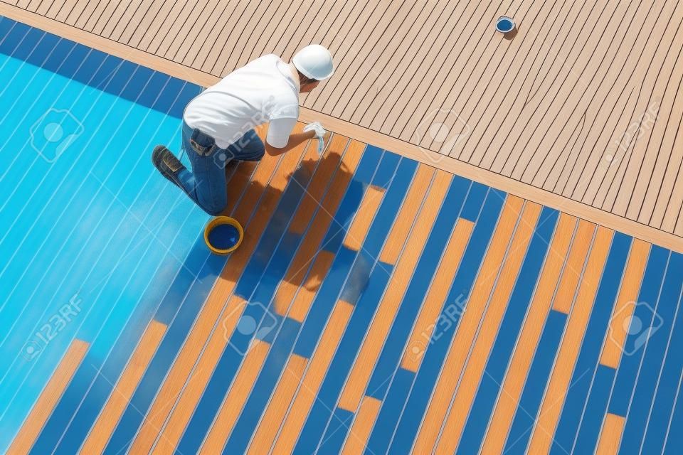 Pracownik malowanie zewnętrzne drewniane Pool Deck, widok z góry
