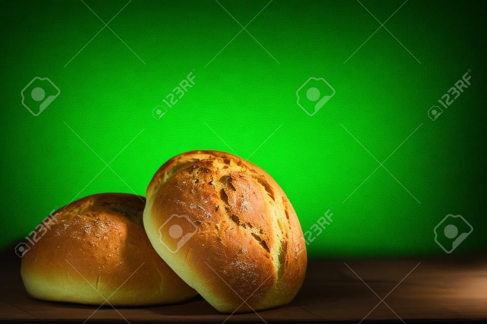 Gros plan de deux pains sur une table en bois avec fond clair flou vert. Notion de nourriture