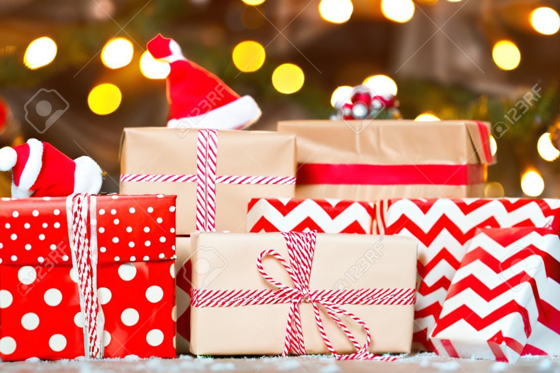 regalos en papel de regalo rojo sobre fondo de árbol de Navidad. pila de cajas debajo del árbol.