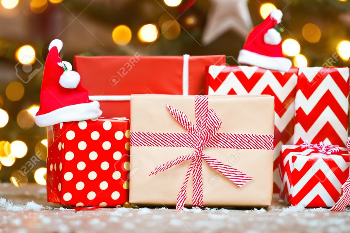 gifts in red wrapping paper on Christmas tree background. stack of boxes under the tree.