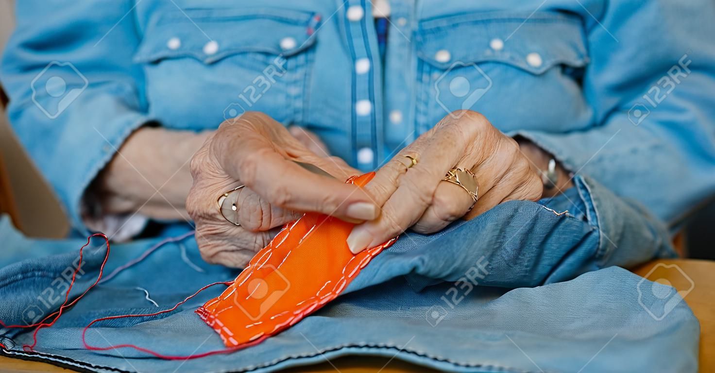 mulher idosa, mãos, costurar, ligado, um, tecido, jeans