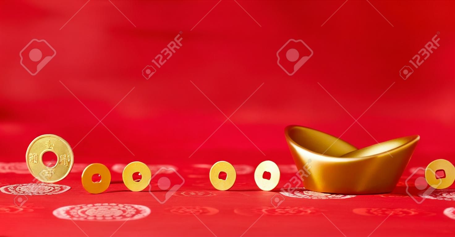 Le monete d'oro che rotolano verso sycee oro (Yuanbao) - tessuto cinese rosso con sfondo motivi orientali