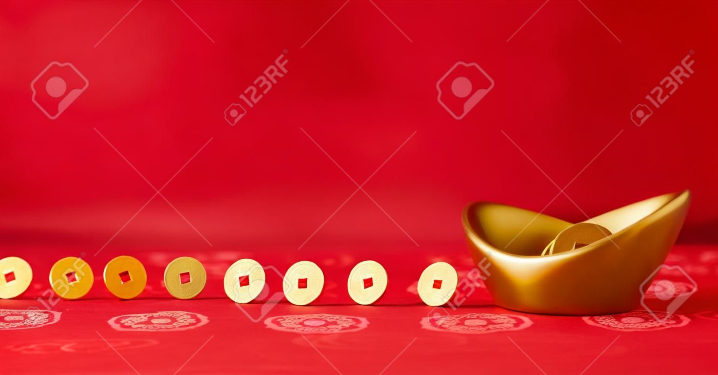 Le monete d'oro che rotolano verso sycee oro (Yuanbao) - tessuto cinese rosso con sfondo motivi orientali