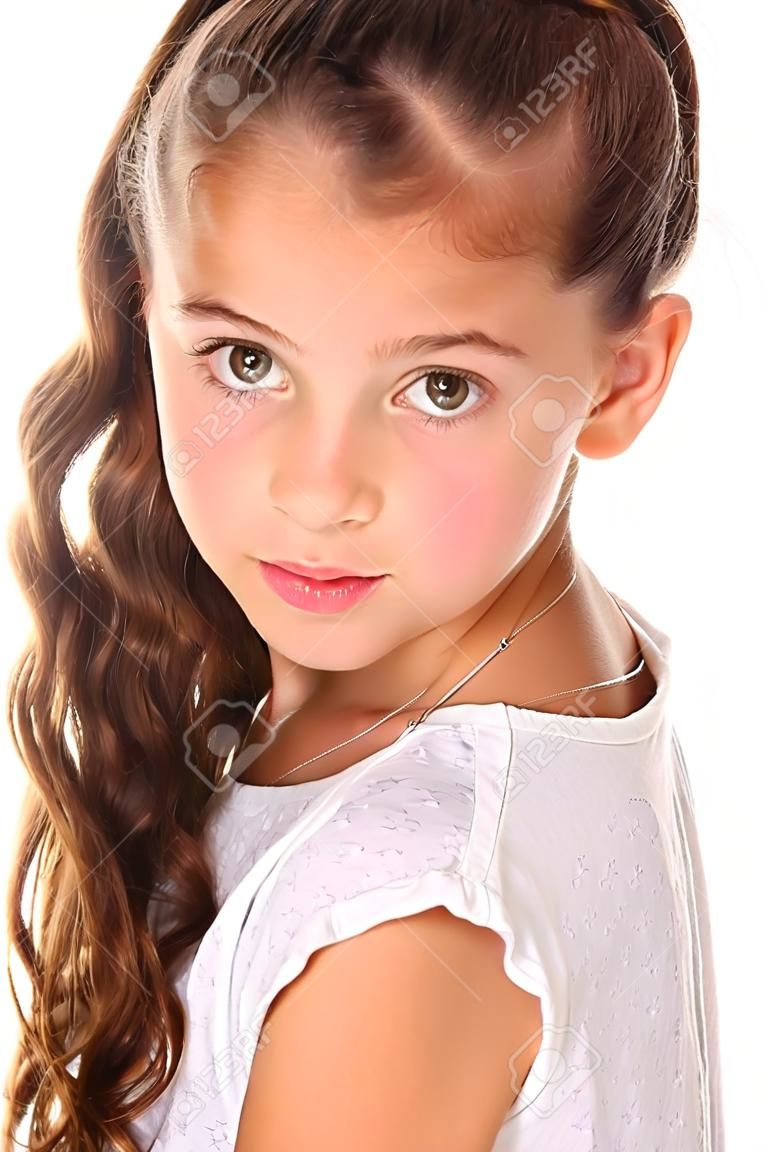 Portrait of a pretty young teenage girl close-up. Adorable preteen with dark hair and charming face on a white background. The image of children's summer fashion.