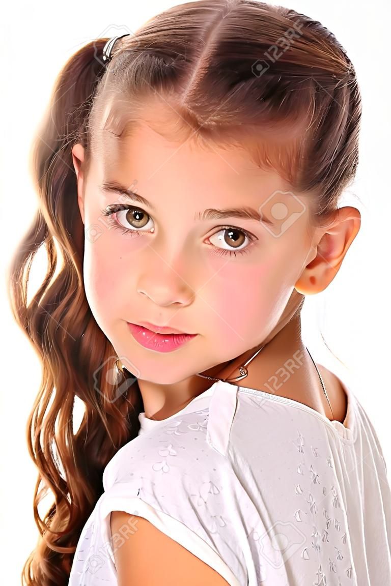 Portrait of a pretty young teenage girl close-up. Adorable preteen with dark hair and charming face on a white background. The image of children's summer fashion.
