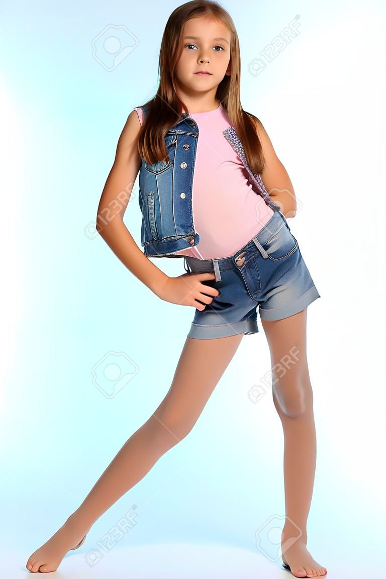 Schönes Mädchen in einer Jeansshorts steht in voller Länge. Elegantes attraktives Kind mit einem schlanken Körper und langen Beinen in Strumpfhosen. Das junge Schulmädchen ist 9 Jahre alt.
