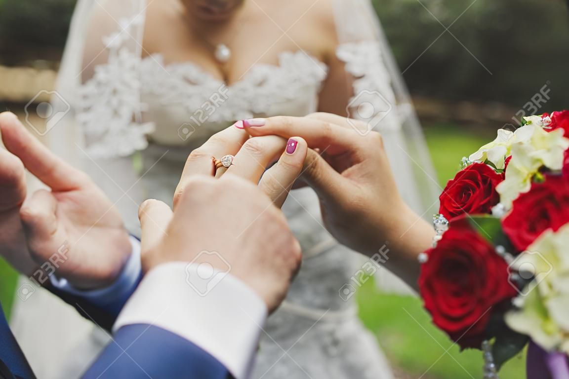la novia y el novio ponen en el dedo un anillo de bodas.