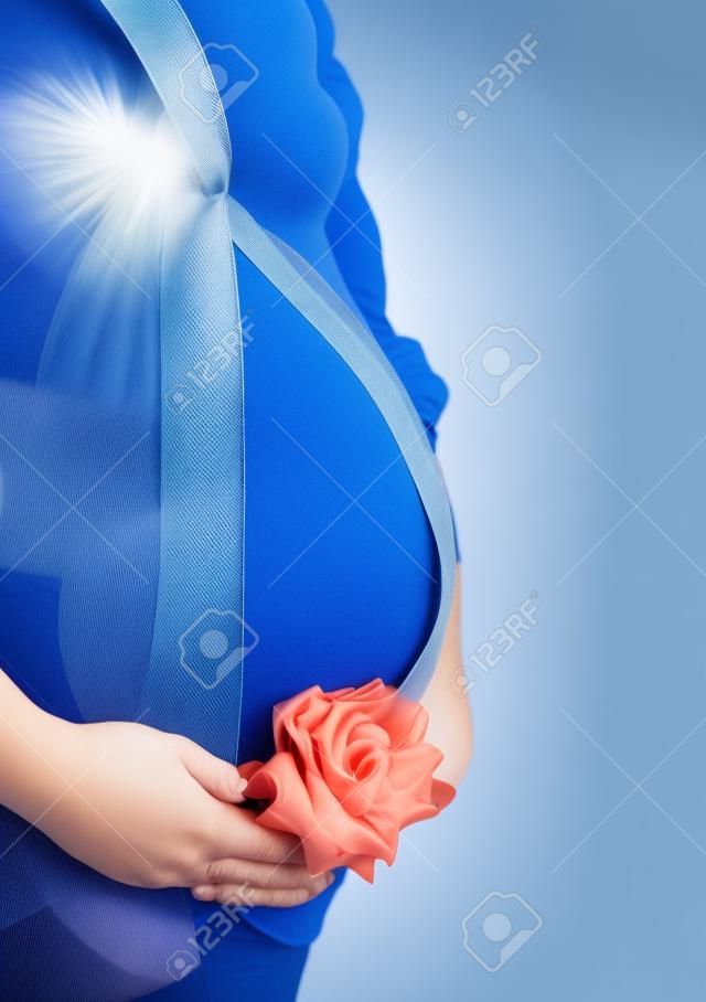 Buik een jonge zwangere vrouw met een blauw lint