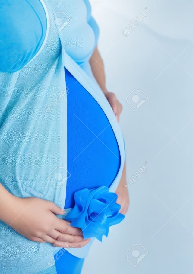 Abdomen a young pregnant woman with a blue ribbon