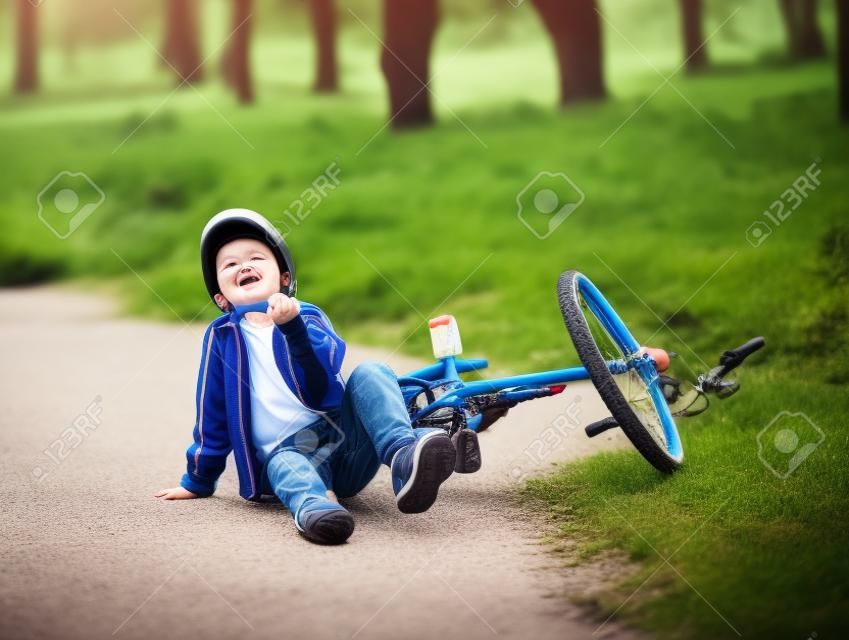 Boy fell from the bike in a park.