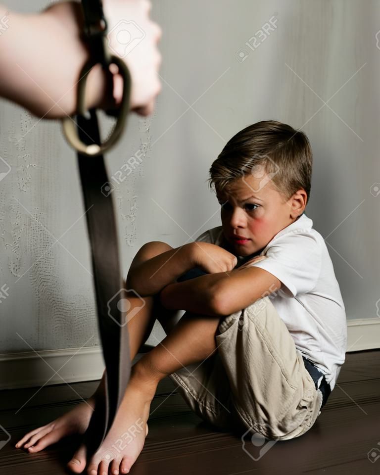Domestic violence: Man's hands with belt and frightened beaten son.