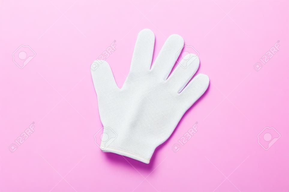 Woman exfoliating hydro glove on pink background. Massage and scrub. Health, spa and beauty concept