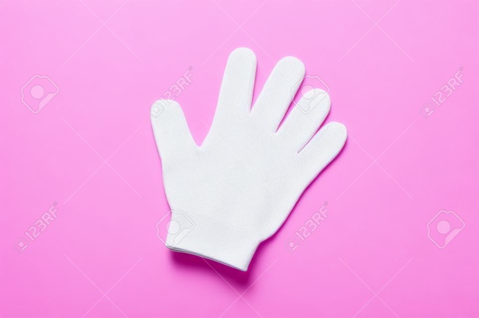 Woman exfoliating hydro glove on pink background. Massage and scrub. Health, spa and beauty concept