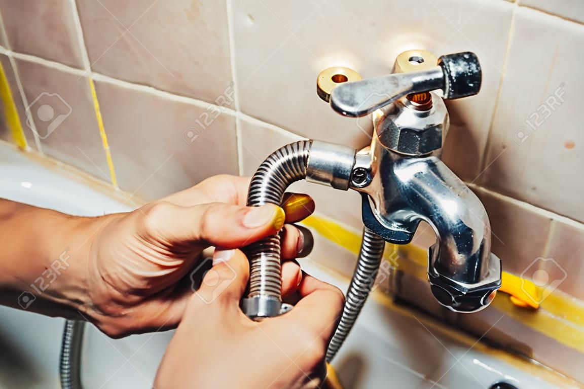 Man repair and fixing leaky faucet in bathroom