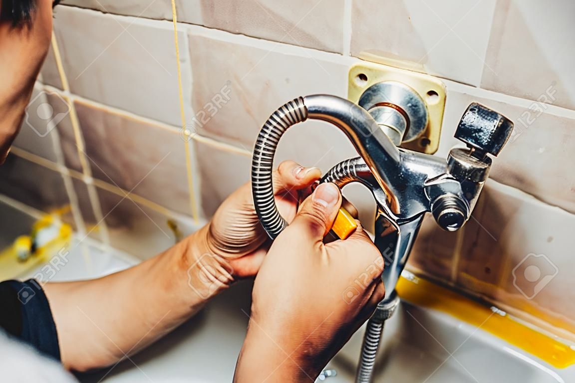 Man repair and fixing leaky faucet in bathroom