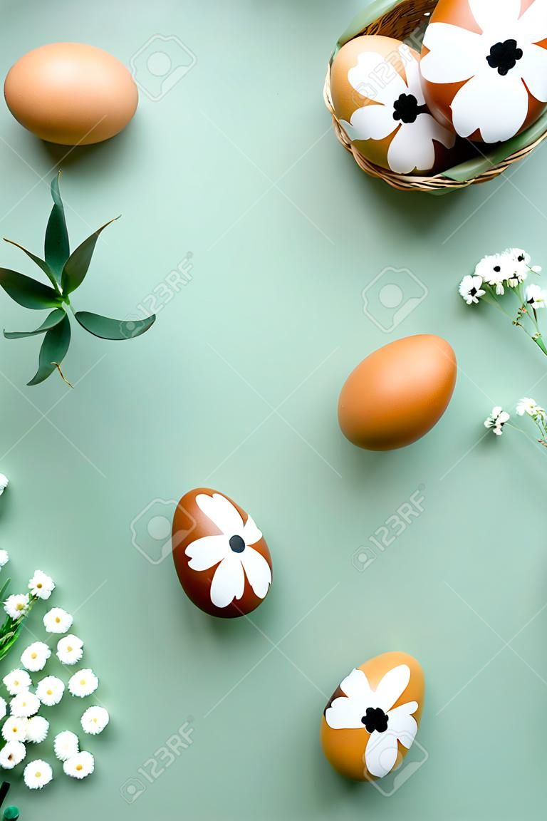 Quadro de ovos de Páscoa e flores no fundo verde pastel. Mockup de bandeira vertical de Páscoa feliz. Lay plana, vista superior, espaço de cópia.