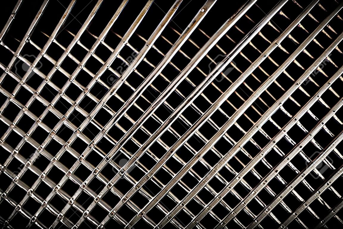 Fond de texture de réseau de grille de ventilation en fer. Motif en métal gris argenté avec trous carrés sur fond noir.