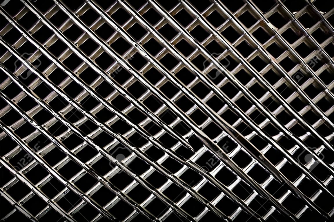 Fondo di struttura del reticolo della griglia di ventilazione del ferro. Modello in metallo grigio argento con fori quadrati su fondo nero.