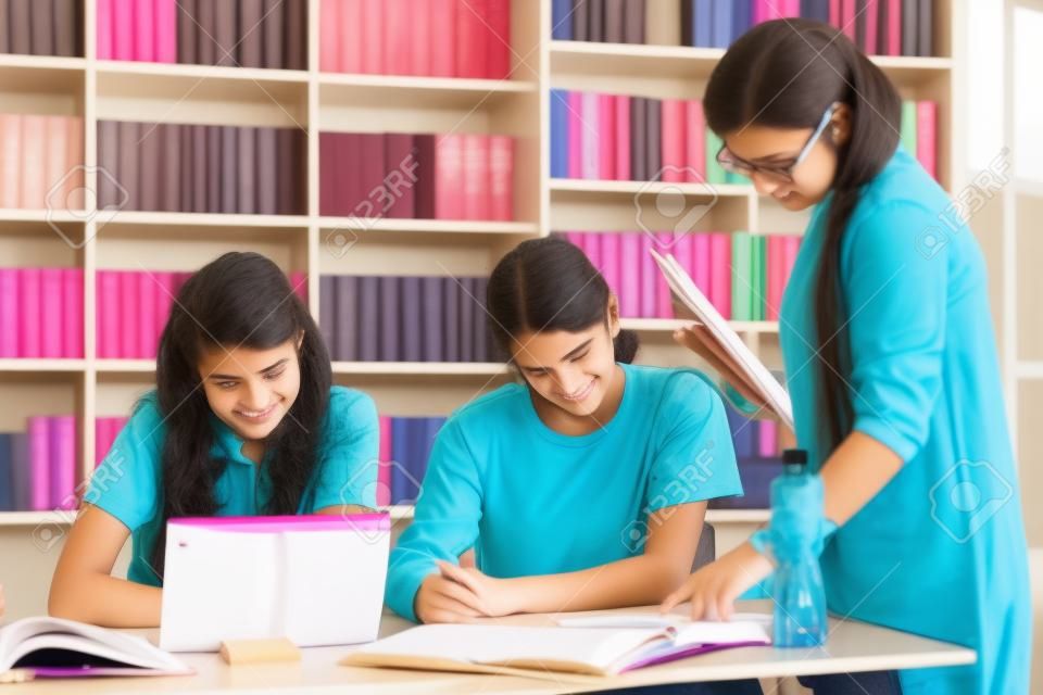 Mädchen im Teenageralter, die in der Bibliothek mit Lehrermentor studieren