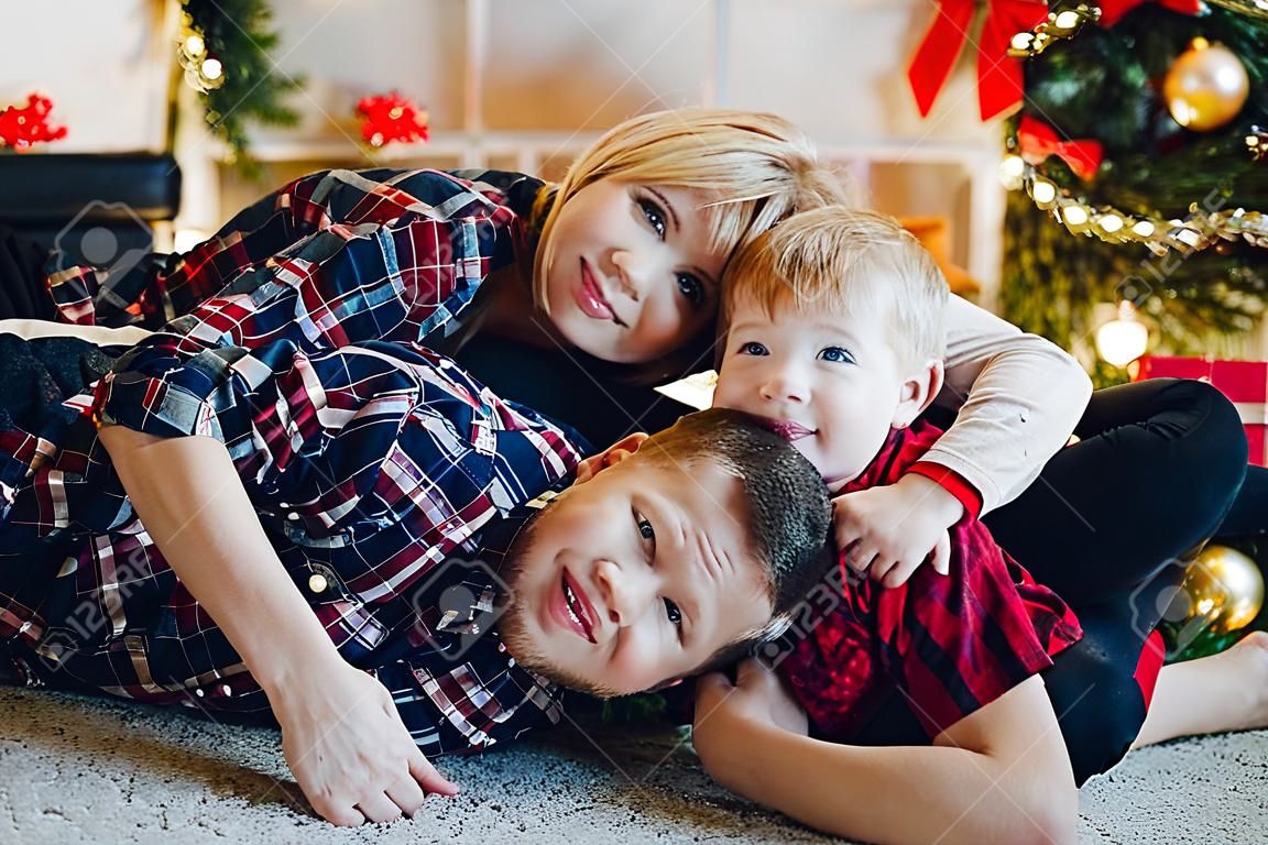 Amorosa familia tirada en el suelo contra la decoración navideña.