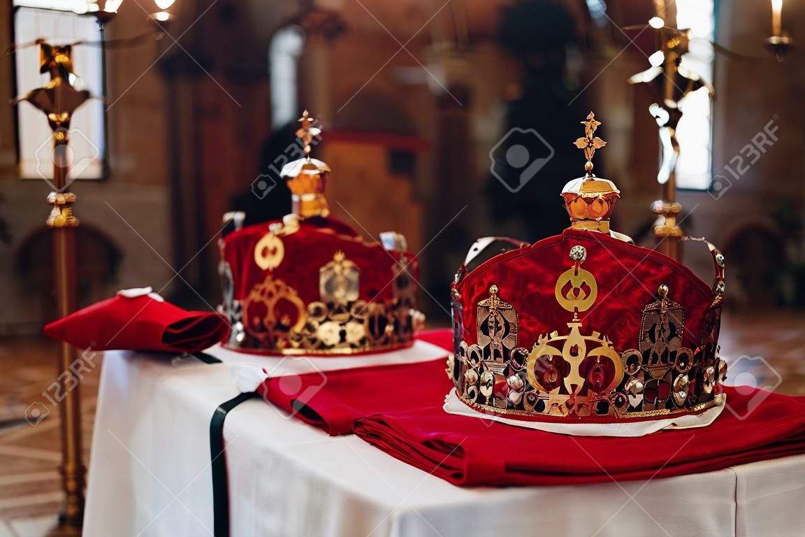 Due belle corone con panno rosso e oro stanno su un tavolo in chiesa prima del battesimo del bambino