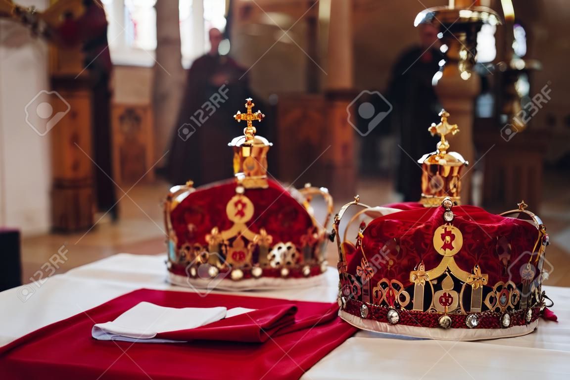 Due belle corone con panno rosso e oro stanno su un tavolo in chiesa prima del battesimo del bambino