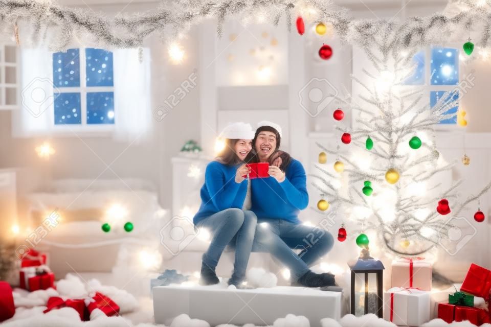 Happy young couple celebrate New Year together at home at the festive Christmas tree