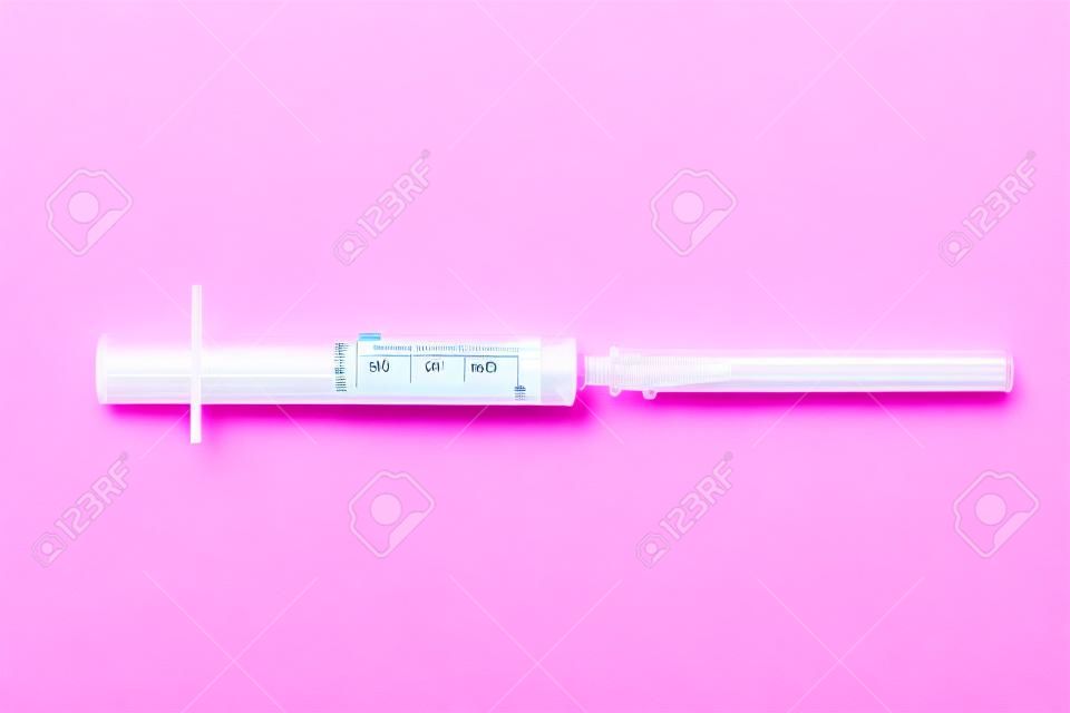 Disposable syringe isolated on a pink background. Healthcare and medicine.