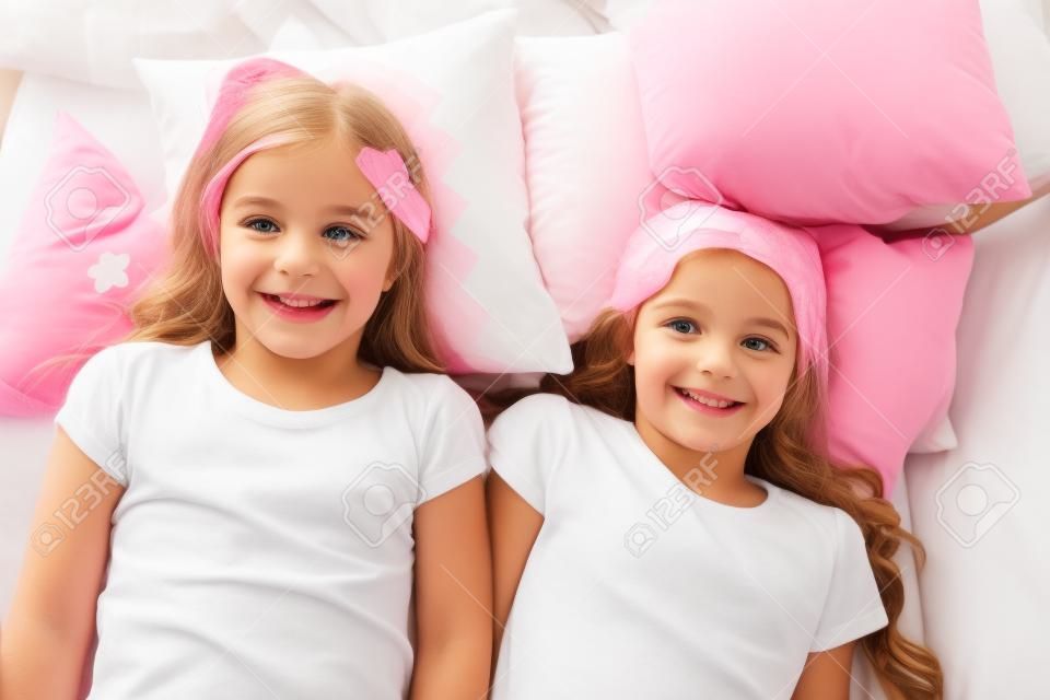 Best friends forever. Girls children lay on bed with cute pillows top view. Pajamas party concept. Girls having fun. Girlish secrets honest and sincere. Friends trust and feel comfortable.
