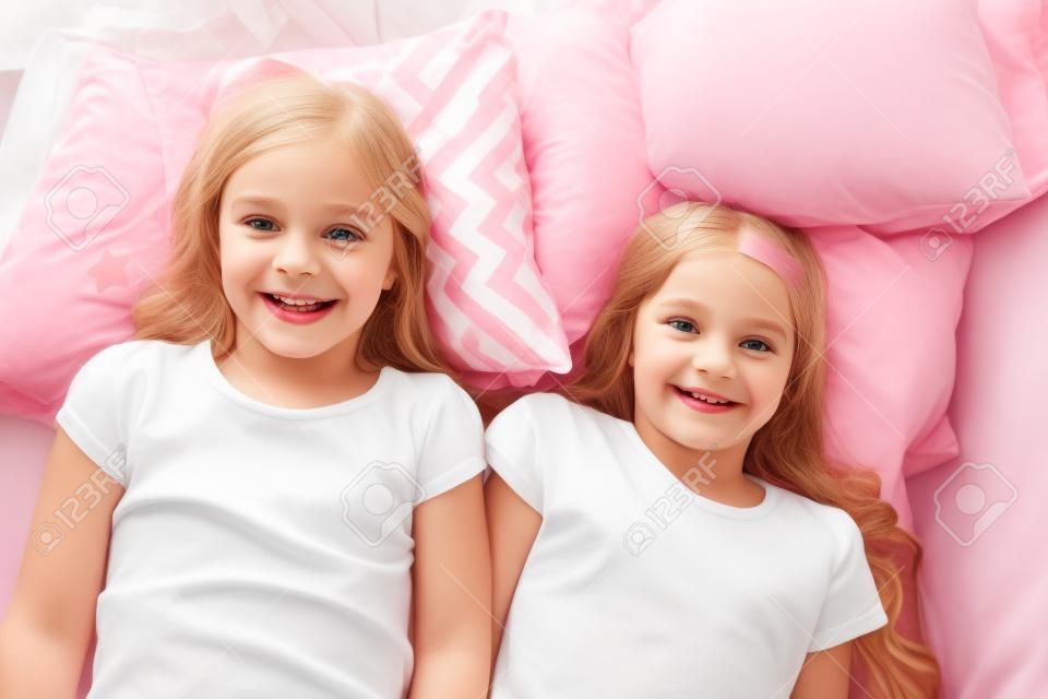 Best friends forever. Girls children lay on bed with cute pillows top view. Pajamas party concept. Girls having fun. Girlish secrets honest and sincere. Friends trust and feel comfortable.