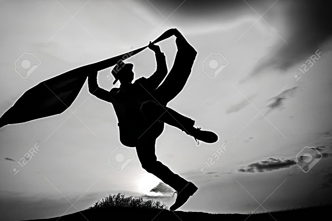 Mann Silhouette springen und tanzen auf Himmelshintergrund. selbstbewusster Geschäftsmann läuft. tägliche Motivation