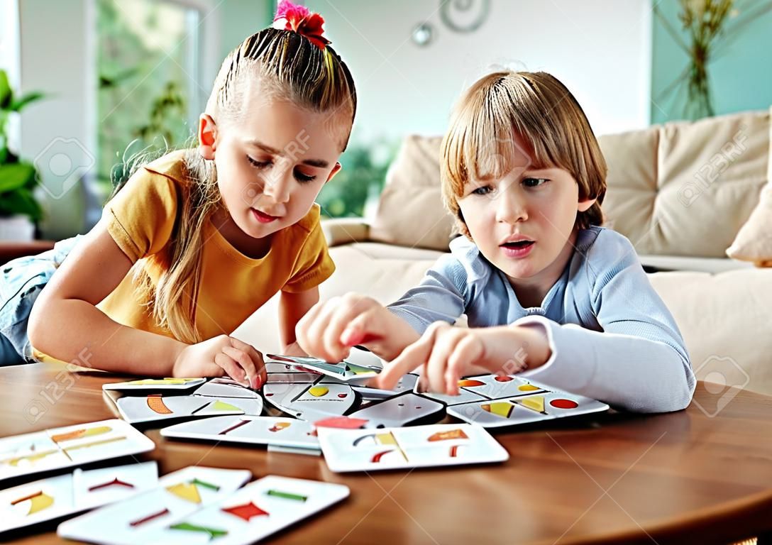 Portret brata i siostry bawiących się razem grając w grę planszową w domu