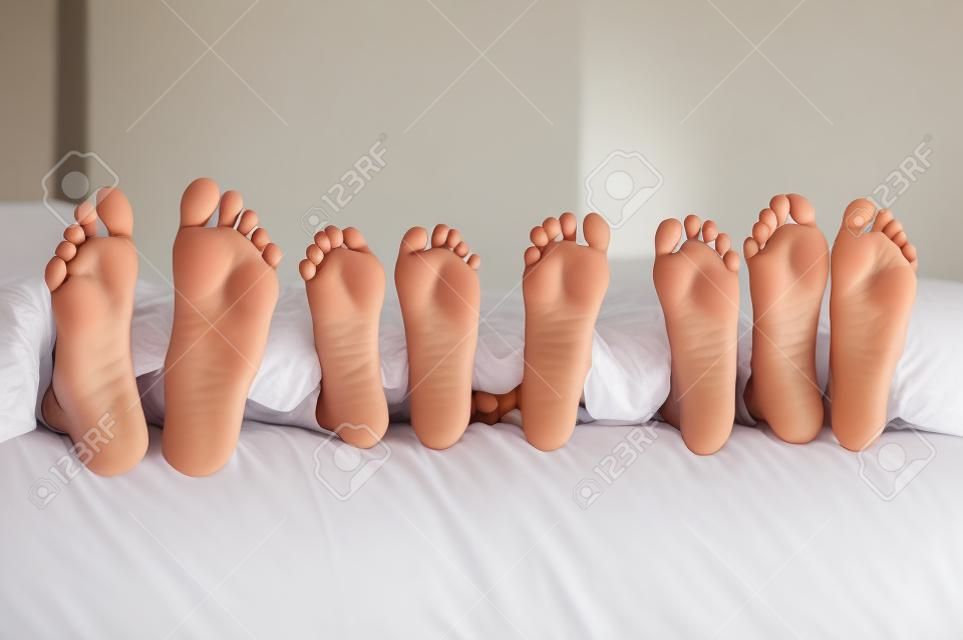 Pies de la familia en la cama