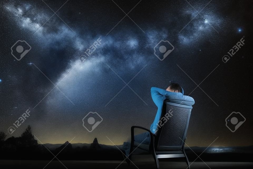 El hombre sentado en el sillón bajo las estrellas