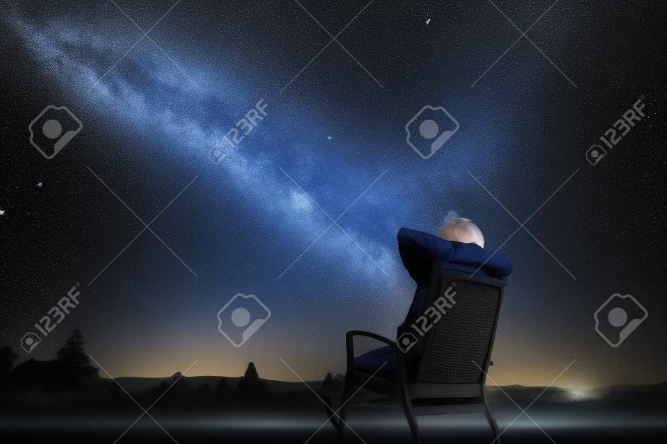 El hombre sentado en el sillón bajo las estrellas