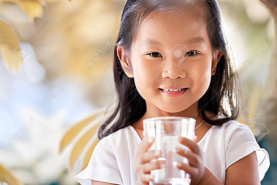 Cute asian little girl holding glass of fresh water in vintage color tone