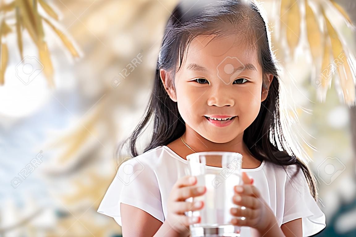 Śliczna azjatycka dziewczynka trzymająca szklankę świeżej wody w odcieniu koloru vintage
