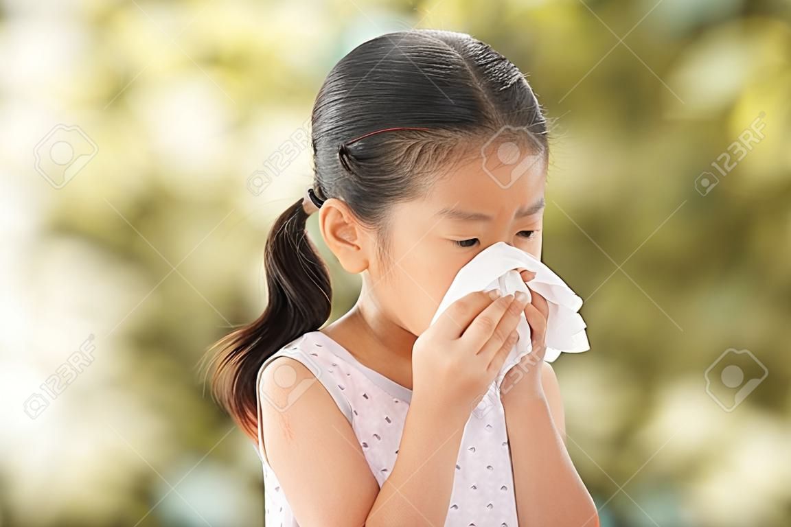 Sick asian little child girl wiping and cleaning nose with tissue on her hand