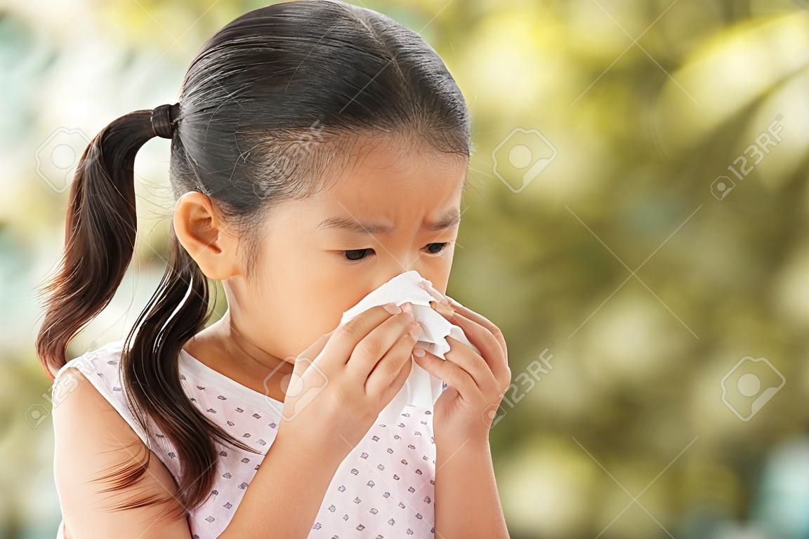 Sick asian little child girl wiping and cleaning nose with tissue on her hand