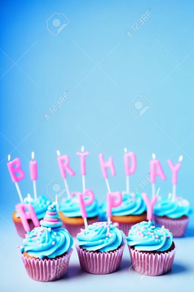 Tortine con glassa blu e rosa e candele di buon compleanno su sfondo blu