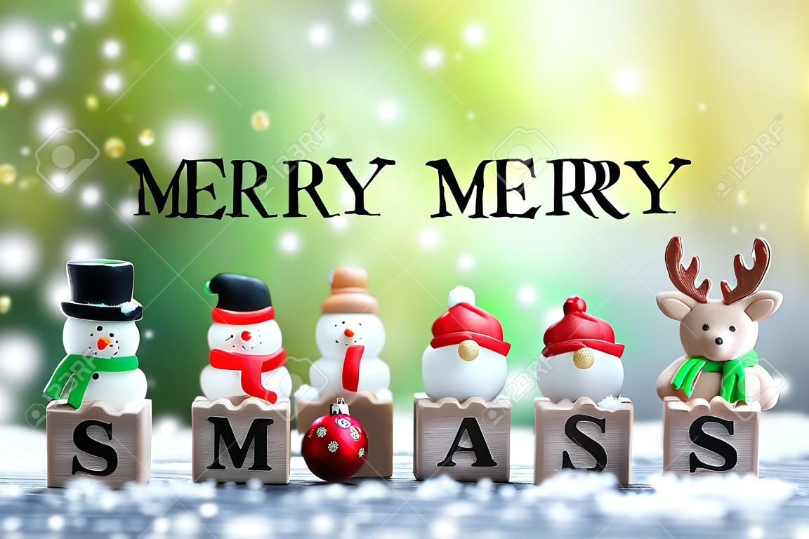 christmas celebration concept, santa doll , wooden cubes X MAS and MERRY letters with snow decoration background green nature