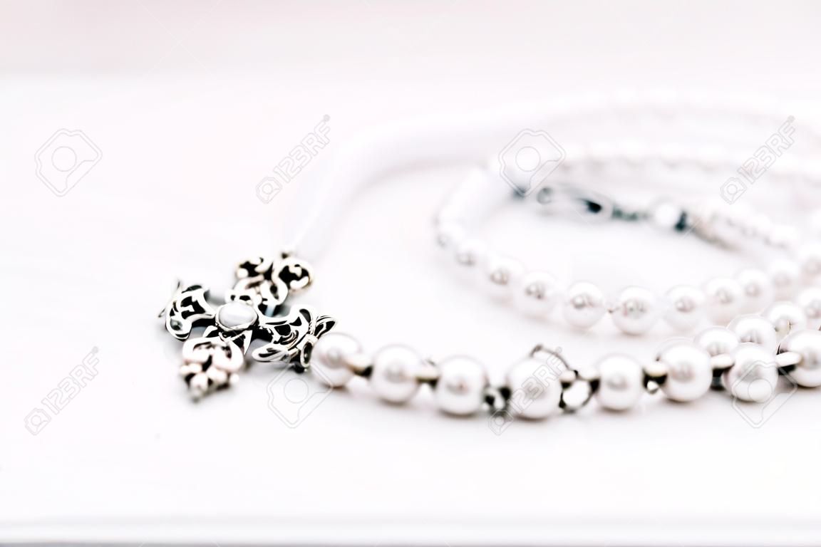 Um colar de contas brancas com correntes de joias sobre um fundo estético branco