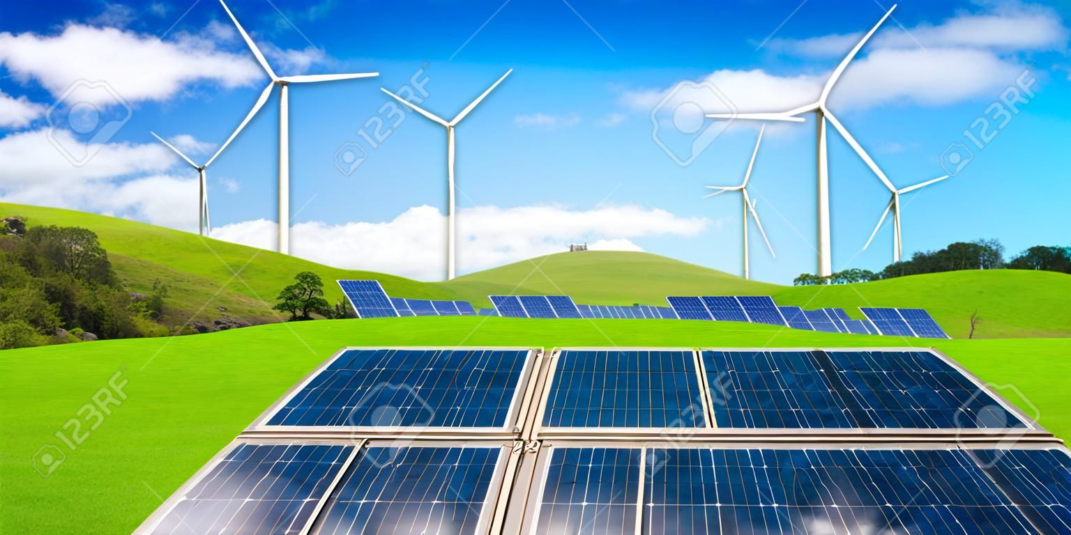 Solar panel and wind turbines farm on a green grass rolling hills against blue sky and white clouds in summer. Concept of renewable clean energy and sustainability business development.
