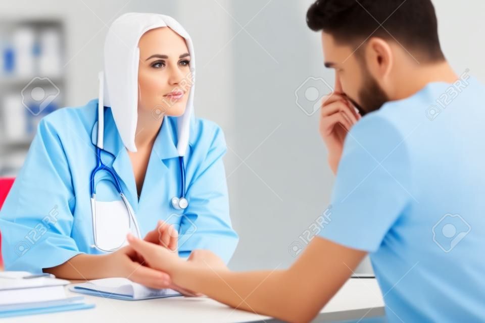 Mulher médica está falando e examinando paciente do sexo masculino no escritório do hospital. Cuidados de saúde e serviço médico.