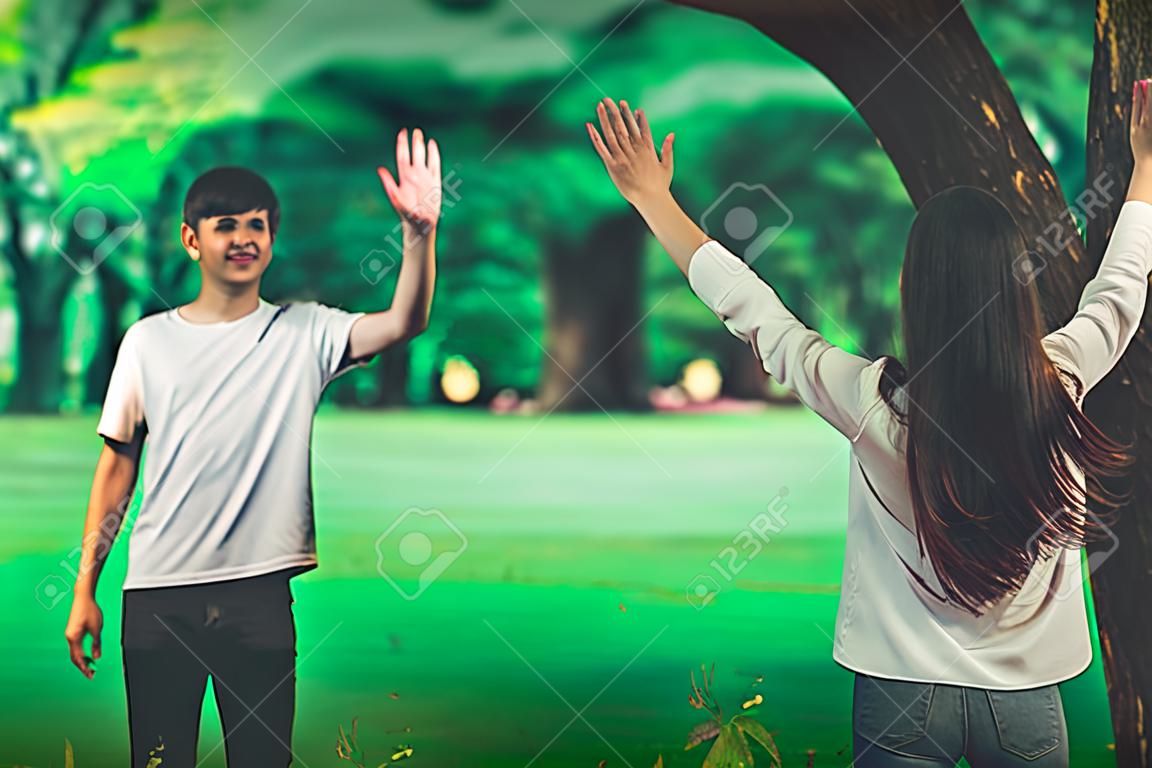 Jóvenes, hombre y mujer saludando o despidiéndose agitando las manos en el parque.