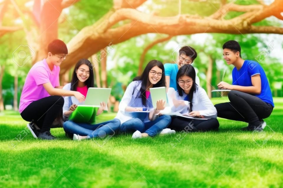 Equipo de jóvenes estudiantes que estudian en un proyecto grupal en el parque de la universidad o la escuela. Aprendizaje feliz, trabajo en equipo comunitario y concepto de amistad juvenil.