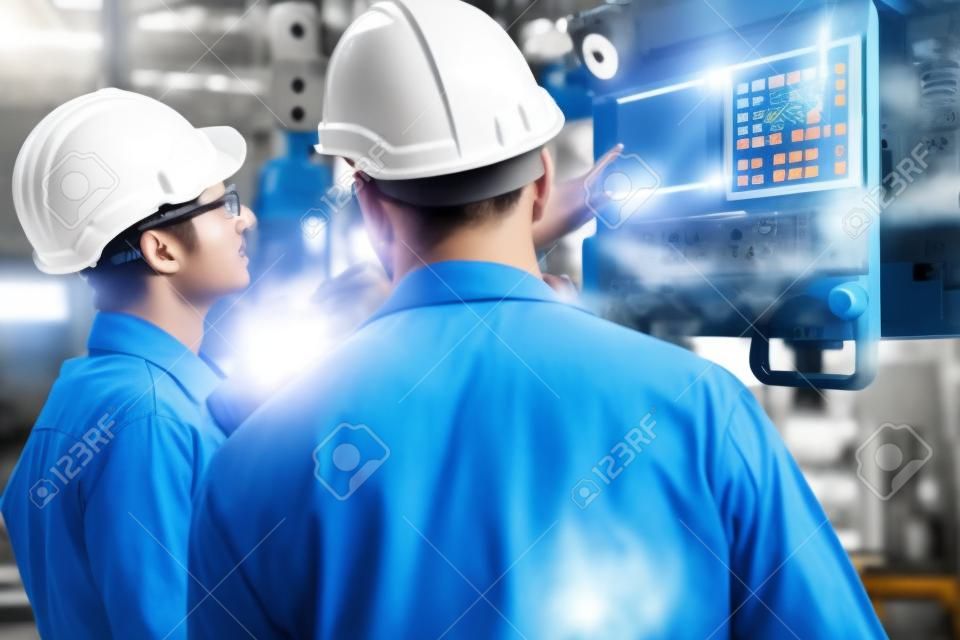 Gruppo di abili operai di fabbrica che utilizzano attrezzature per macchine in officina. Concetto di tecnologia per persone dell'industria e dell'ingegneria.